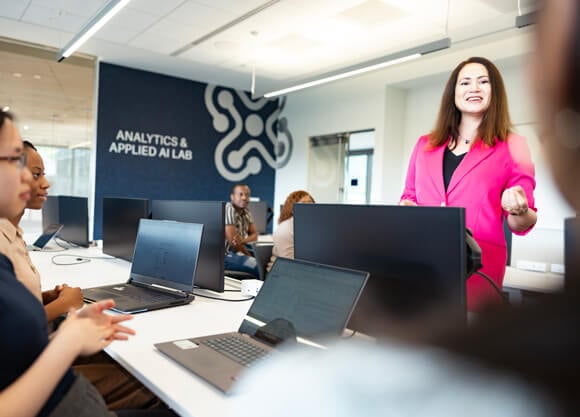 A woman speaking to students in the Analytics & Applied AI Lab