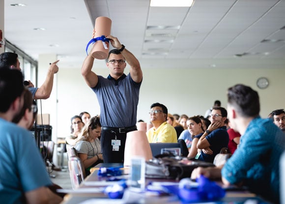 A male instructor holds a manikin arm with a tourniquet on it