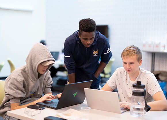 Three students around a computer during the annual Hack-a-Thon